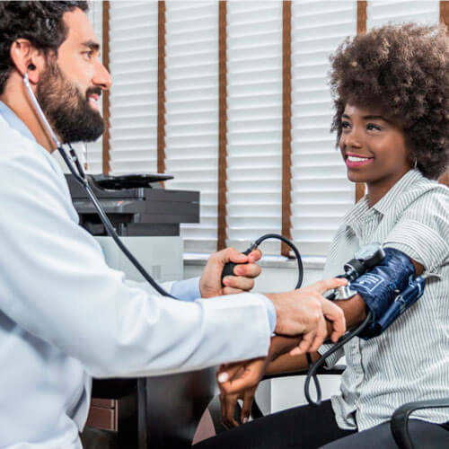 Médico conferindo a pressão arterial da paciente para concluir o Exame Admissional